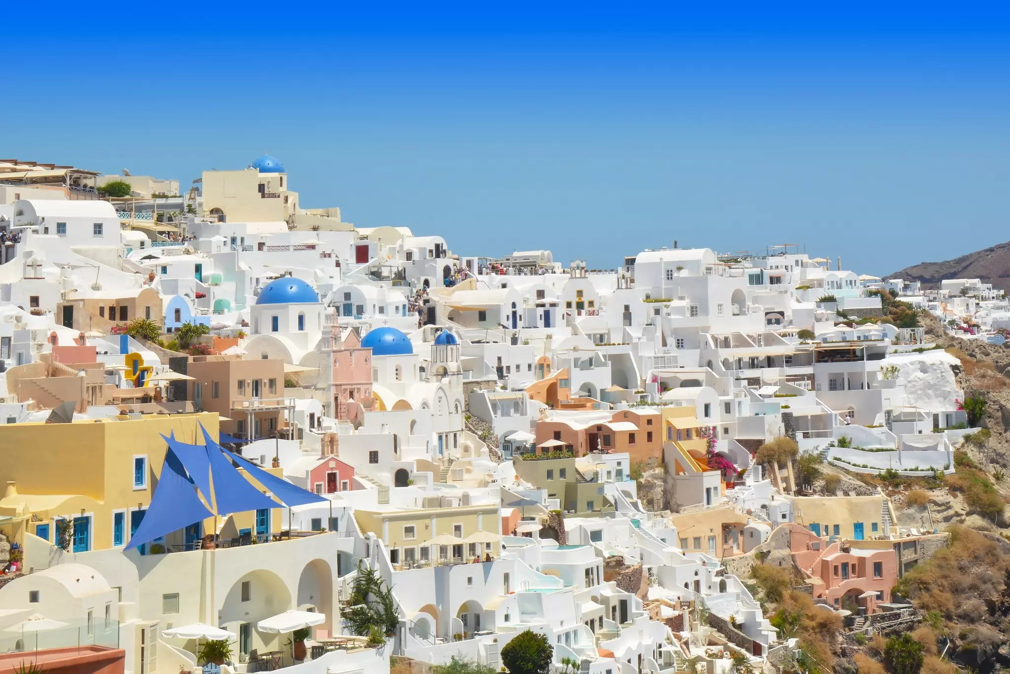 Greek village with traditional whitewashed houses and blue-domed churches overlooking the caldera.