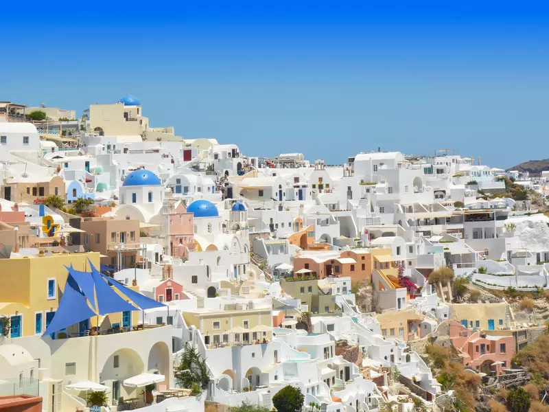 Greek village with traditional whitewashed houses and blue-domed churches overlooking the caldera.