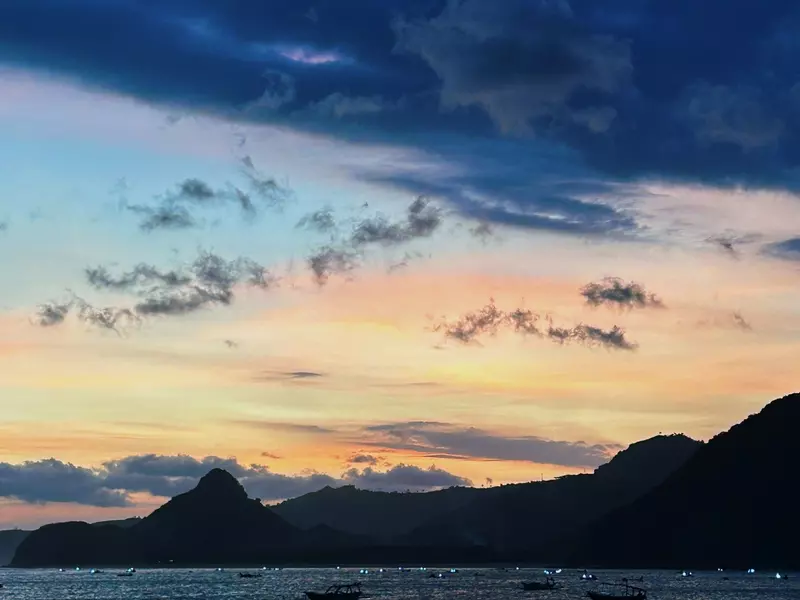 A sunset over a beach casts colorful streaks across the sky. 