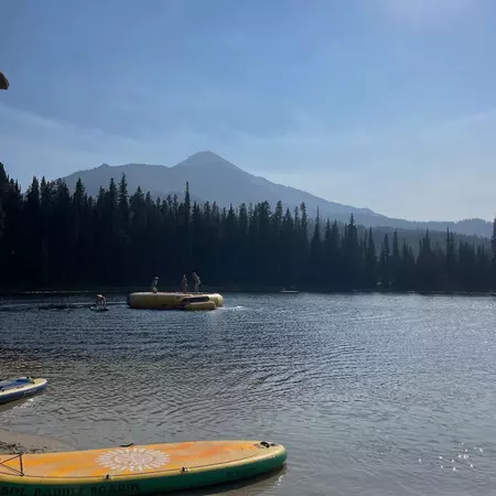 A lake surrounded by woodland, with people bouncing on a large inflatable