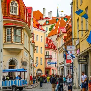 A pedestrian street in a historic center that has buildings with red roofs.