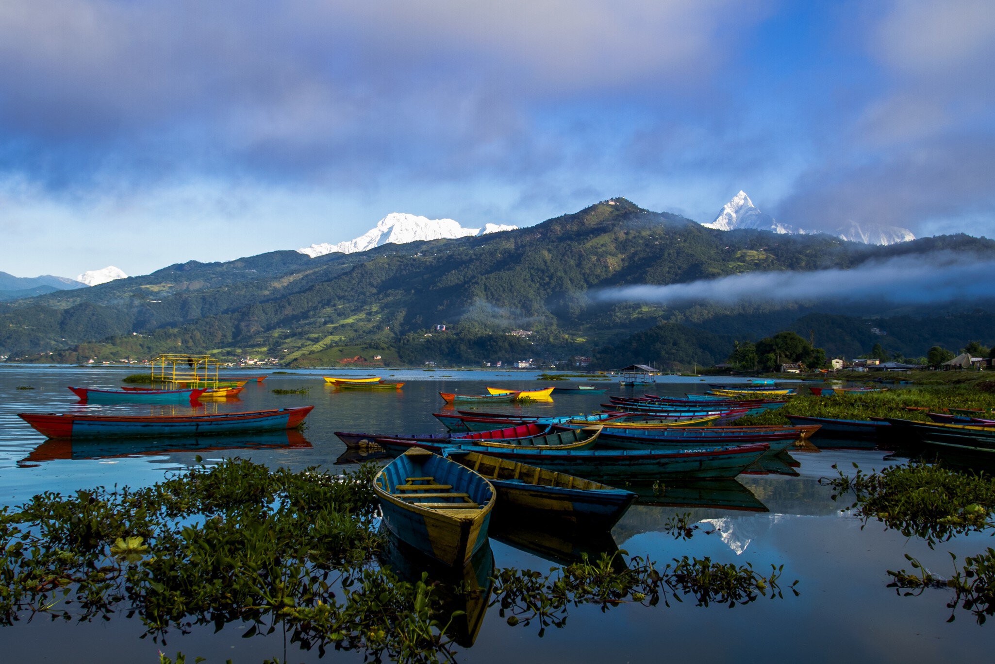 Small wooden boats float at the edge of a lake