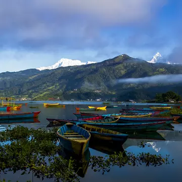 Small wooden boats float at the edge of a lake