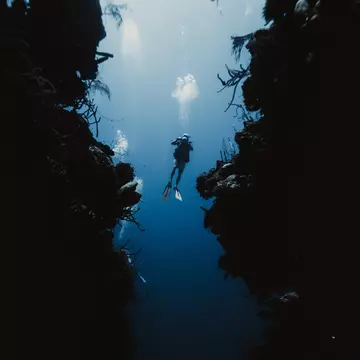 A solo scuba diver with excellent buoyancy hovers between walls in an underwater passage