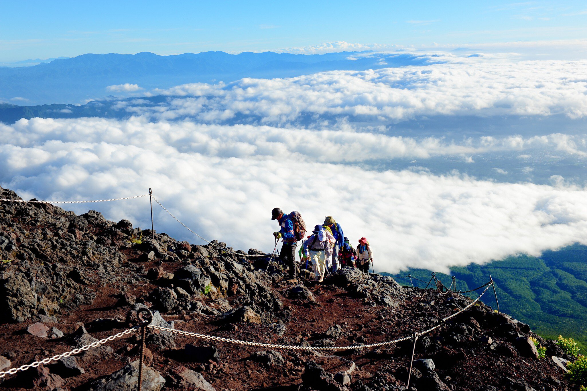 A group of climbers on a rocky mountain slope above the clouds.