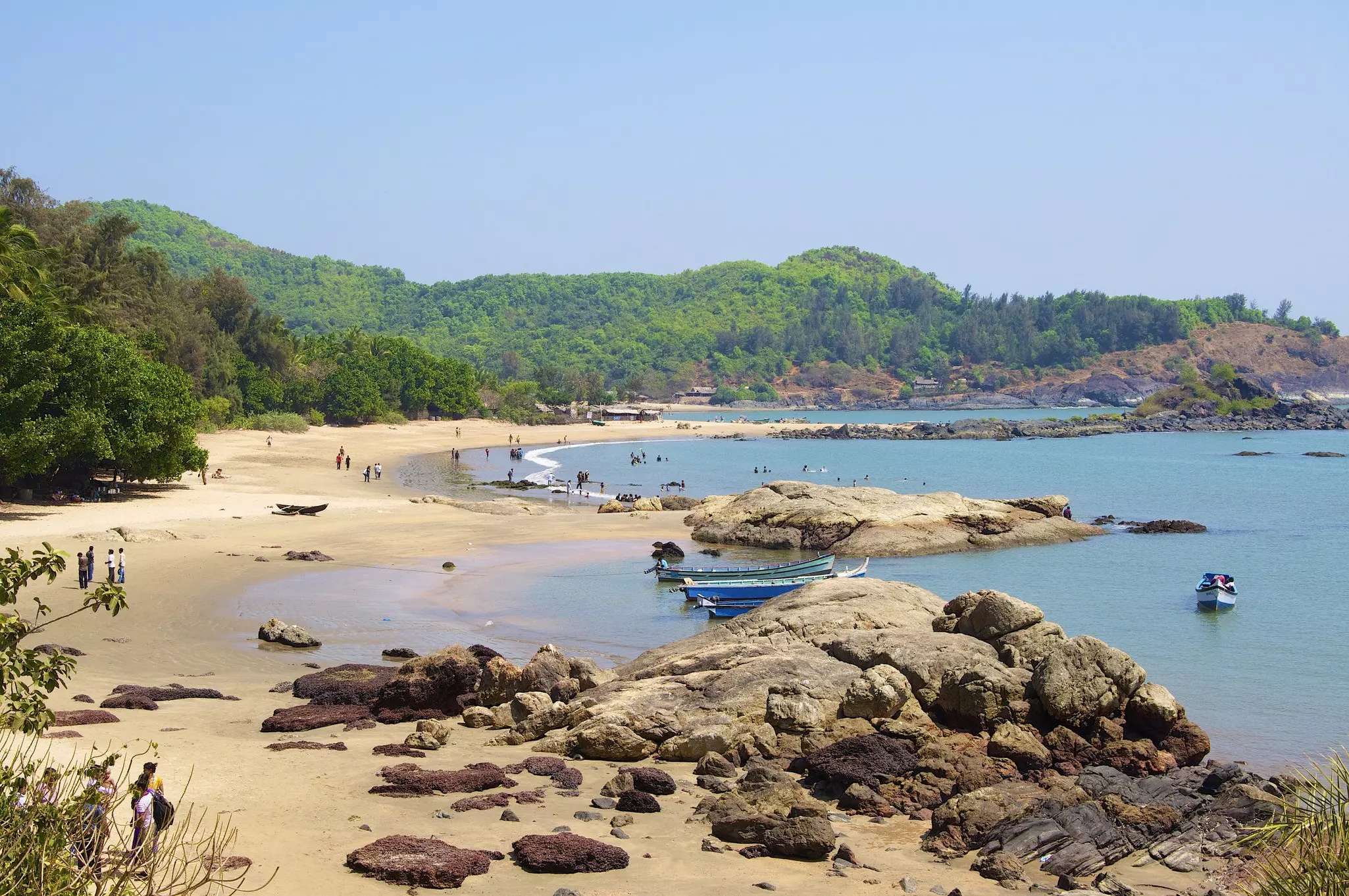 Fishing boats next to Om beach with green forest on the surrounding cliffs