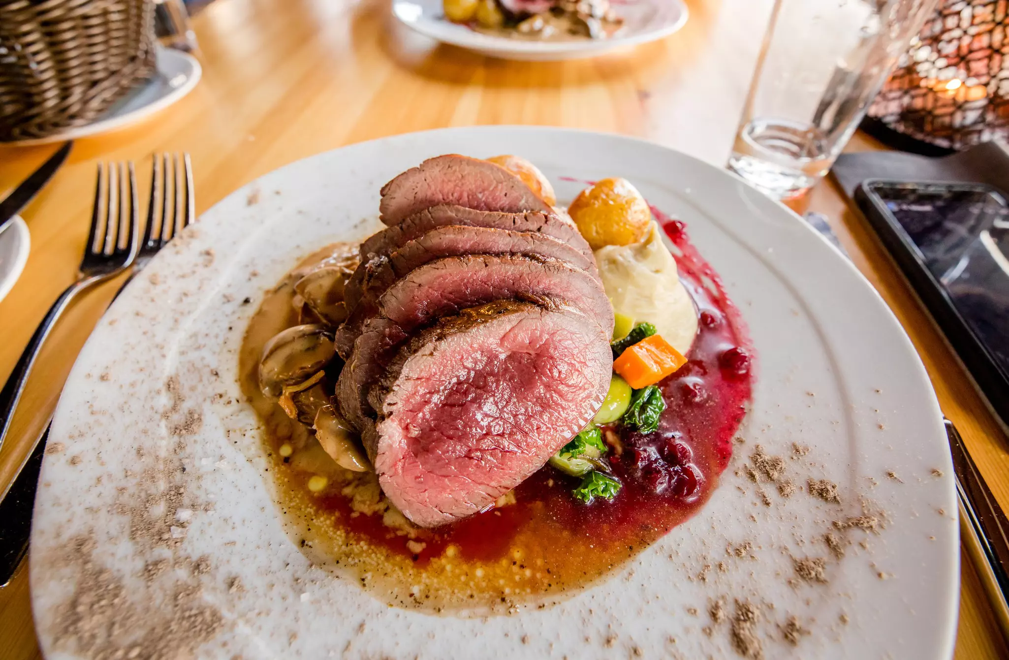 A closer look of a gourmet reindeer steak served with savory sauce and potatoes