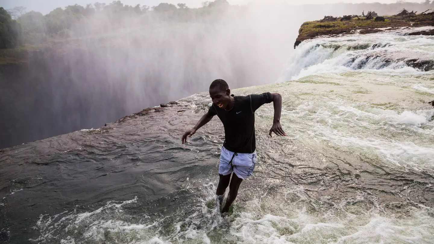 A man jumping into the water at the naturally formed 'Devil's Pool' at Victoria Falls.