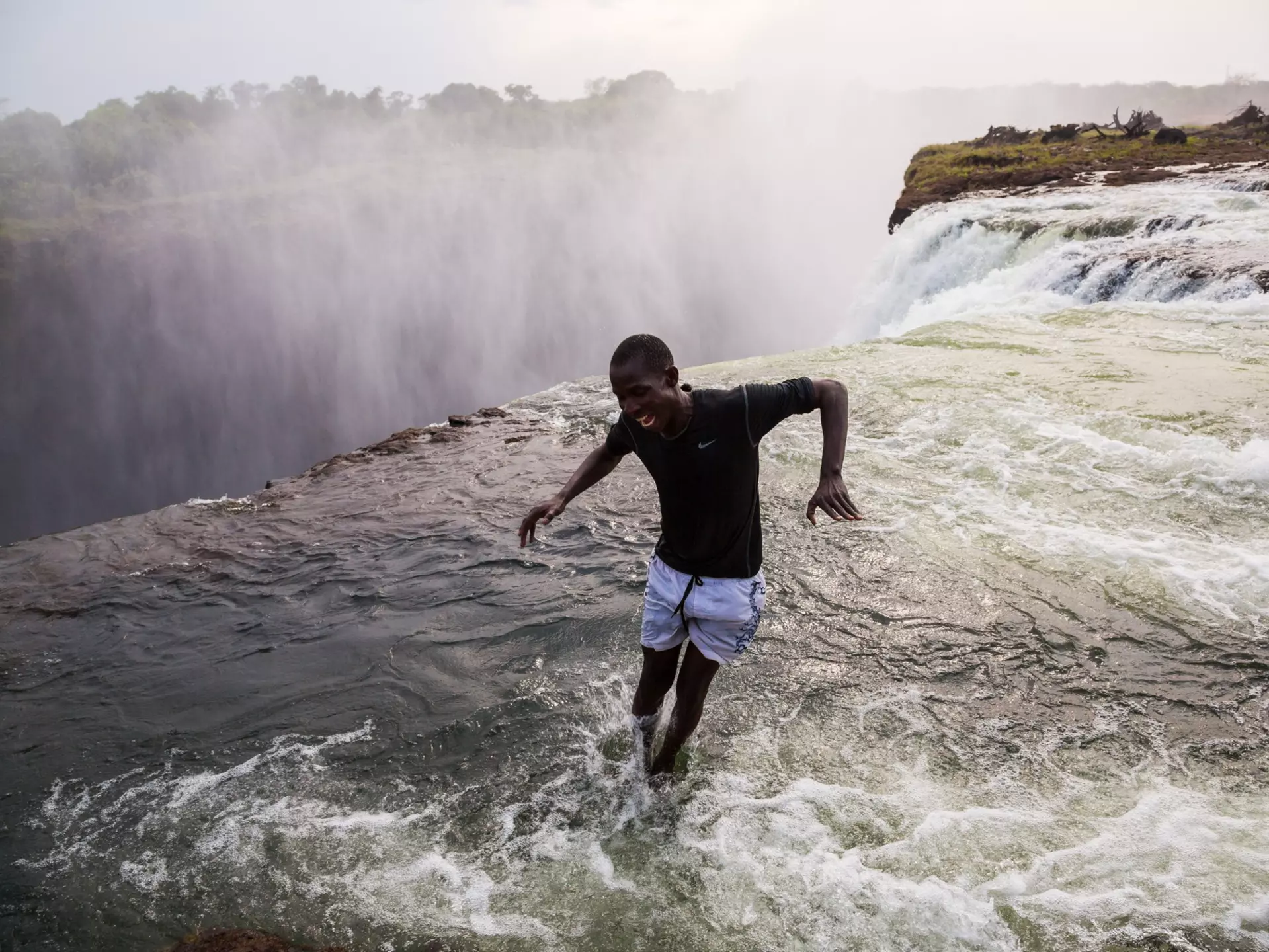 A man jumping into the water at the naturally formed 'Devil's Pool' at Victoria Falls.
