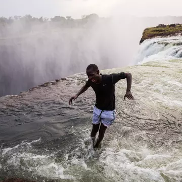 A man jumping into the water at the naturally formed 'Devil's Pool' at Victoria Falls.