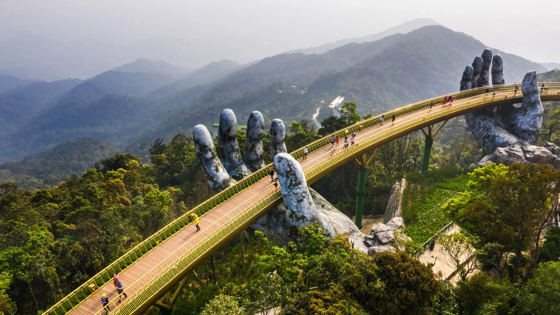 Aerial view of the Golden Bridge is lifted by two giant hands in the tourist resort on Ba Na Hill in Danang, Vietnam. Ba Na mountain resort is a favorite destination for tourists