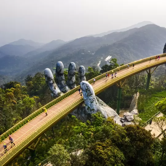 Aerial view of the Golden Bridge is lifted by two giant hands in the tourist resort on Ba Na Hill in Danang, Vietnam. Ba Na mountain resort is a favorite destination for tourists