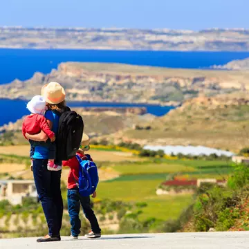 A mother with two kids overlooking a scenic mountain vista, seen from the back