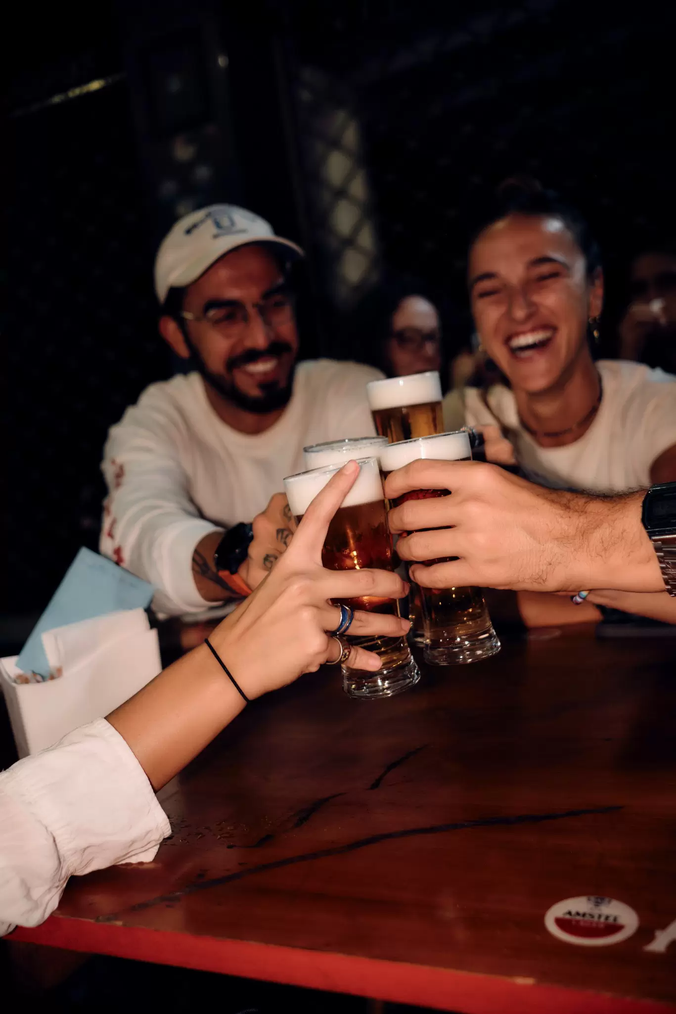 Group of people smiling and doing a cheers with glasses of beer.