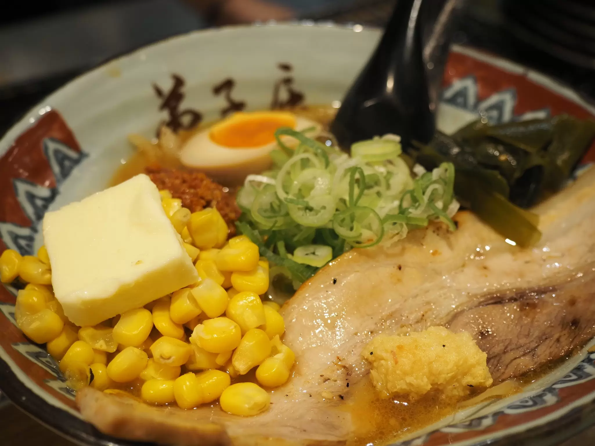A bowl with meat, vegetables, egg and a topping of corn and butter: Ramen Teshikaga in Ganso Ramen Yokocho, Sapporo, Japan.