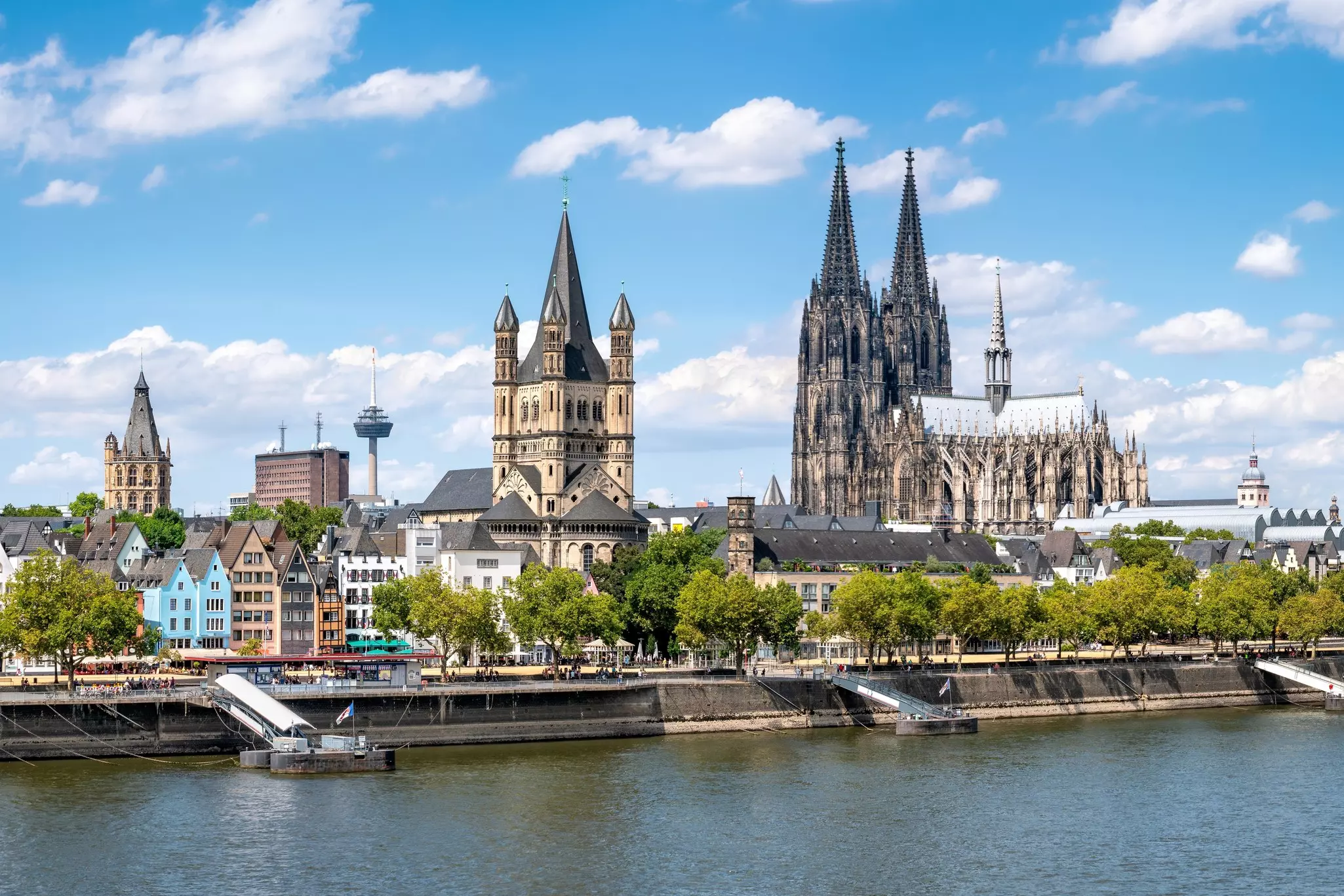 A dark Gothic cathedral with spires by a blue river.