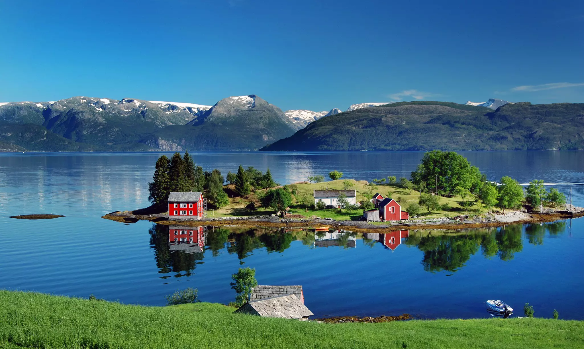 Red and white houses on a small island in a fjord 