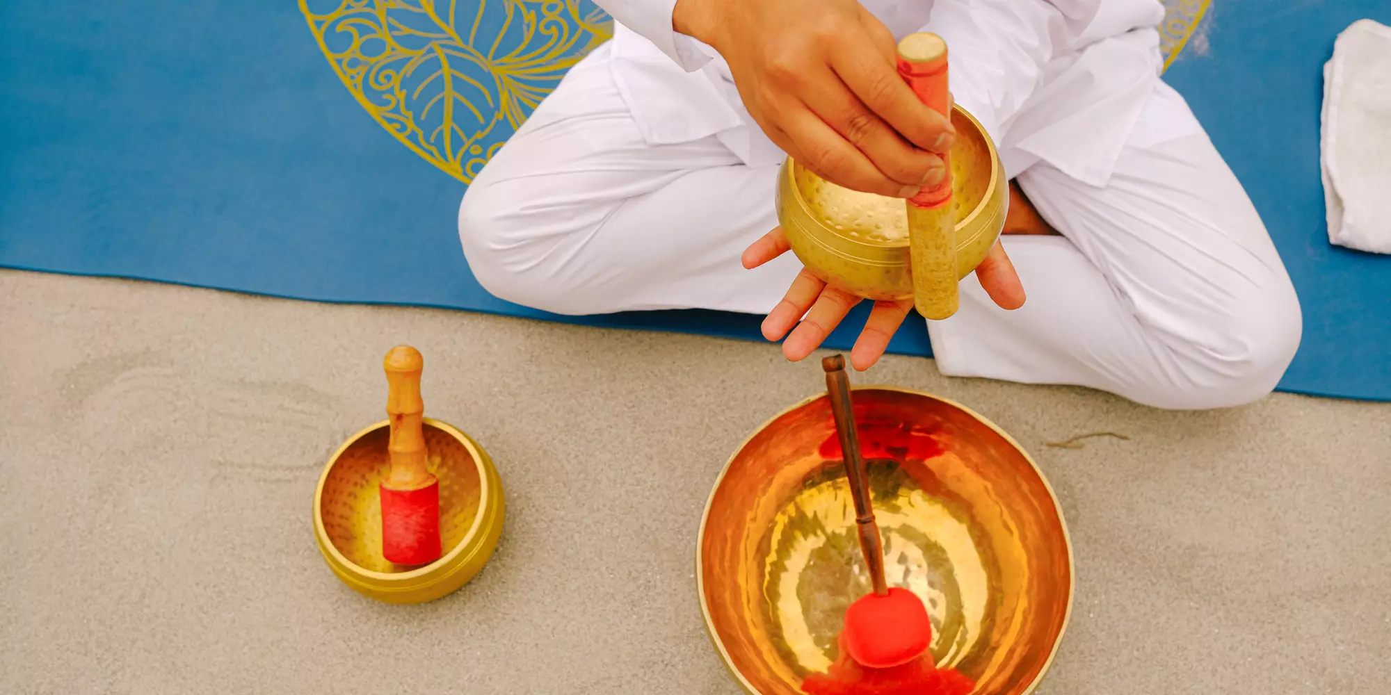 A yoga teacher chimes a sound bowl near the Ganges. Rishikesh, India. 2025.