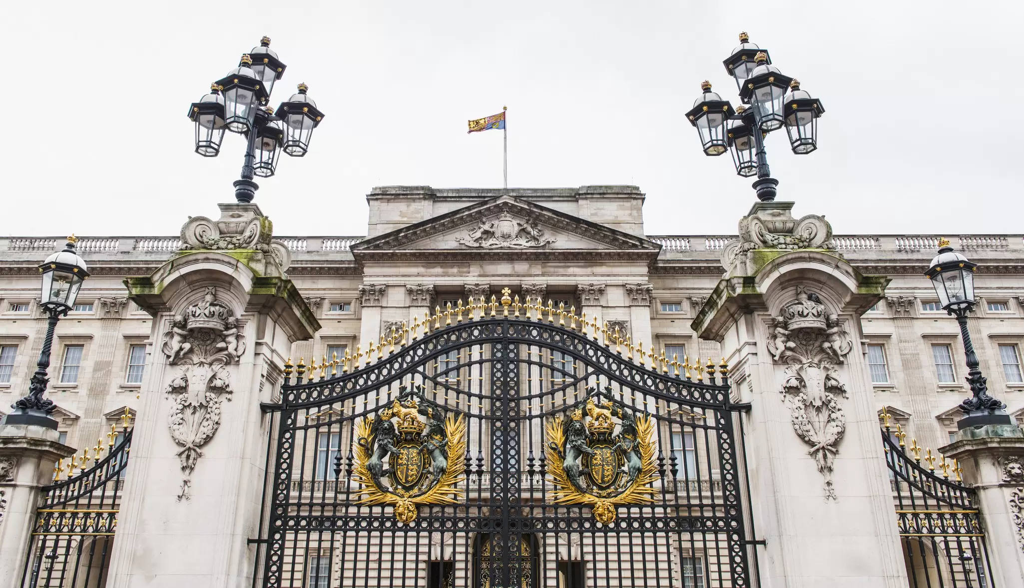 A large black wrought-iron gate outside a huge palace building
