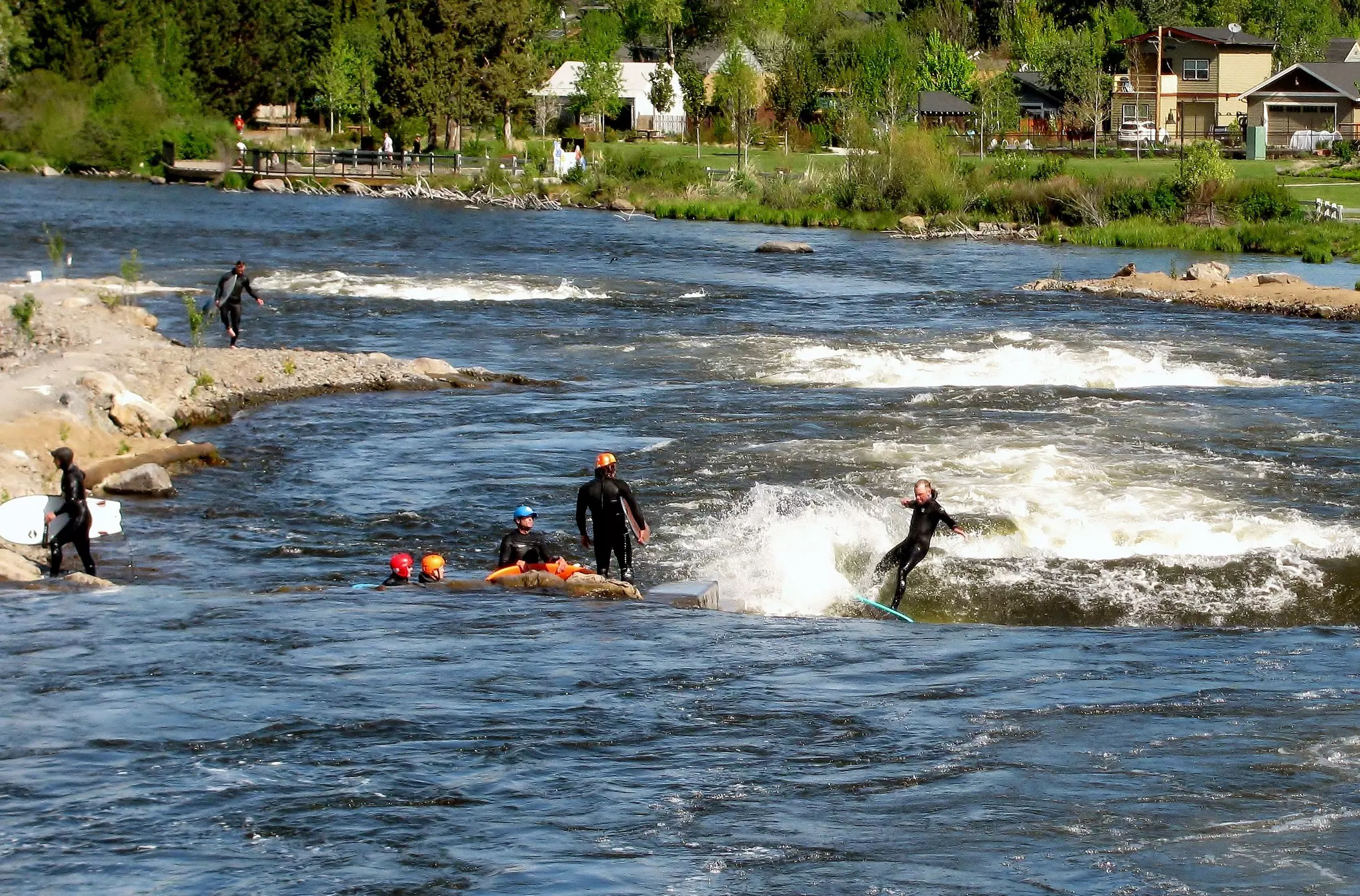 Group of people river surfing Bend Whitewater Park in the Deschutes River, Bend, Oregon, Pacific Northwest, USA