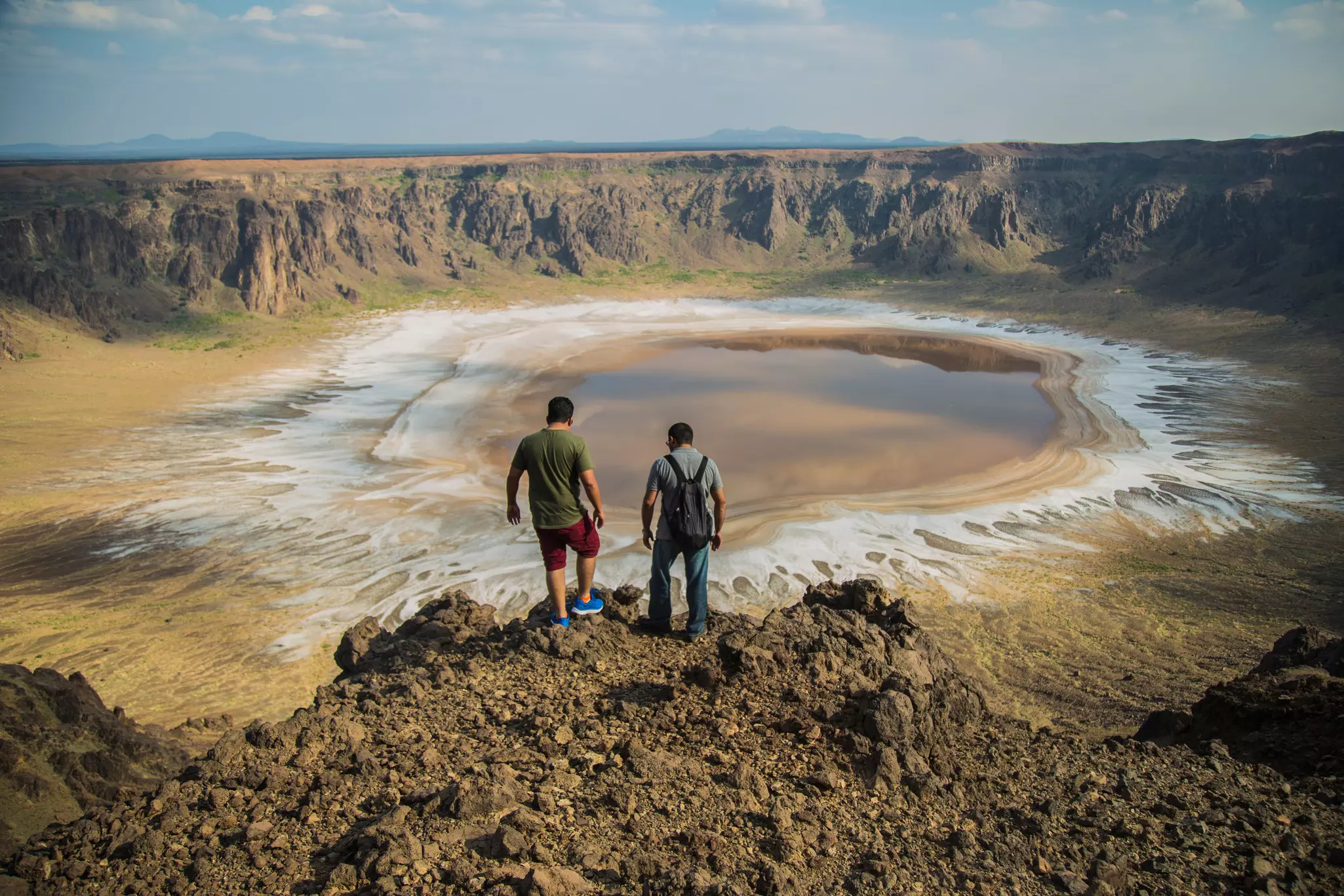 Two people stand at the edge of a crater.