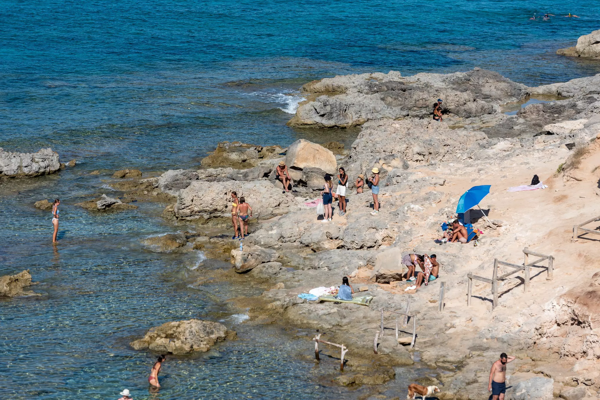 People sunbathe on a rocky beach