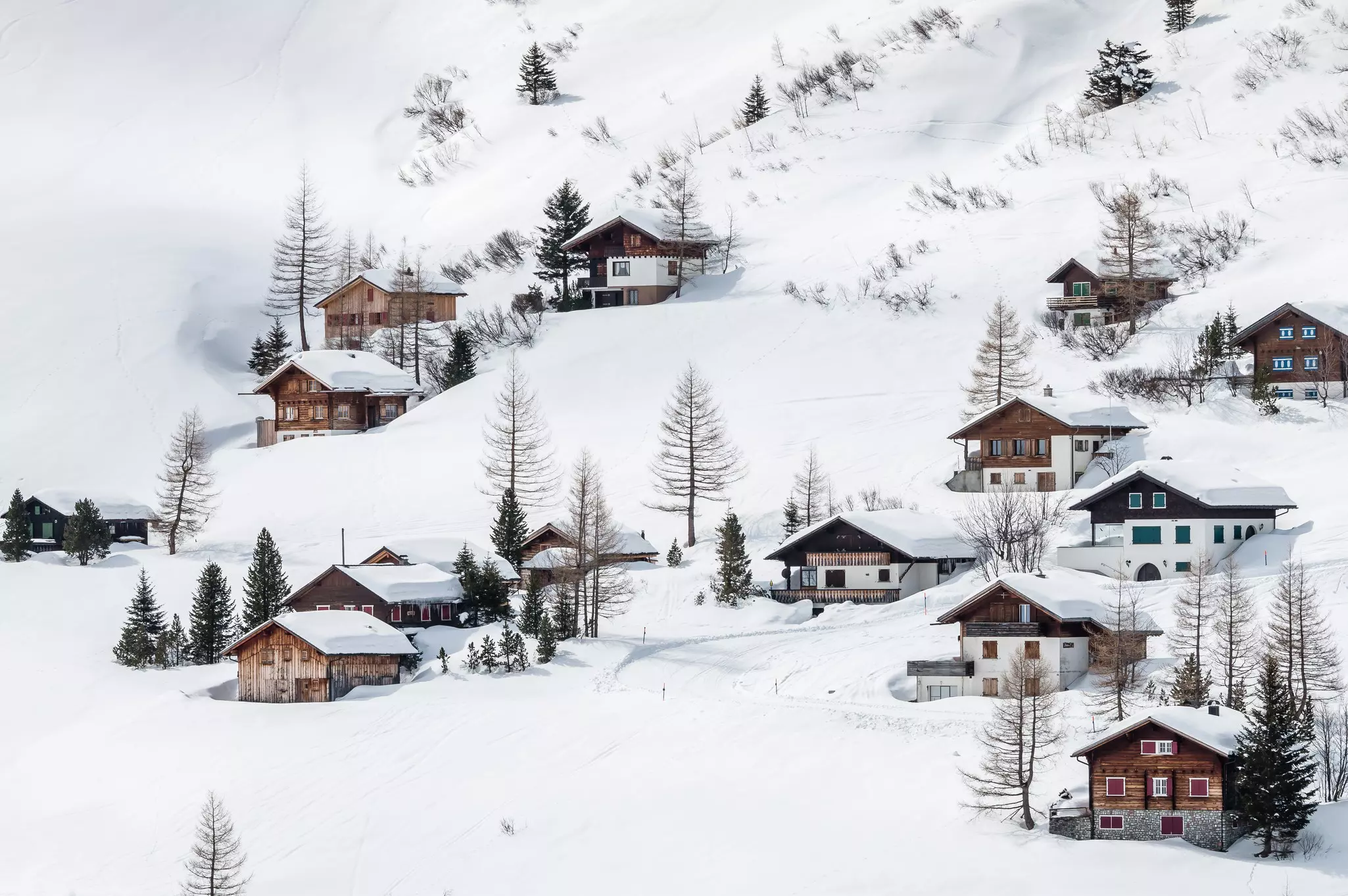 A cluster of wooden chalets in a snowy mountain landscape.