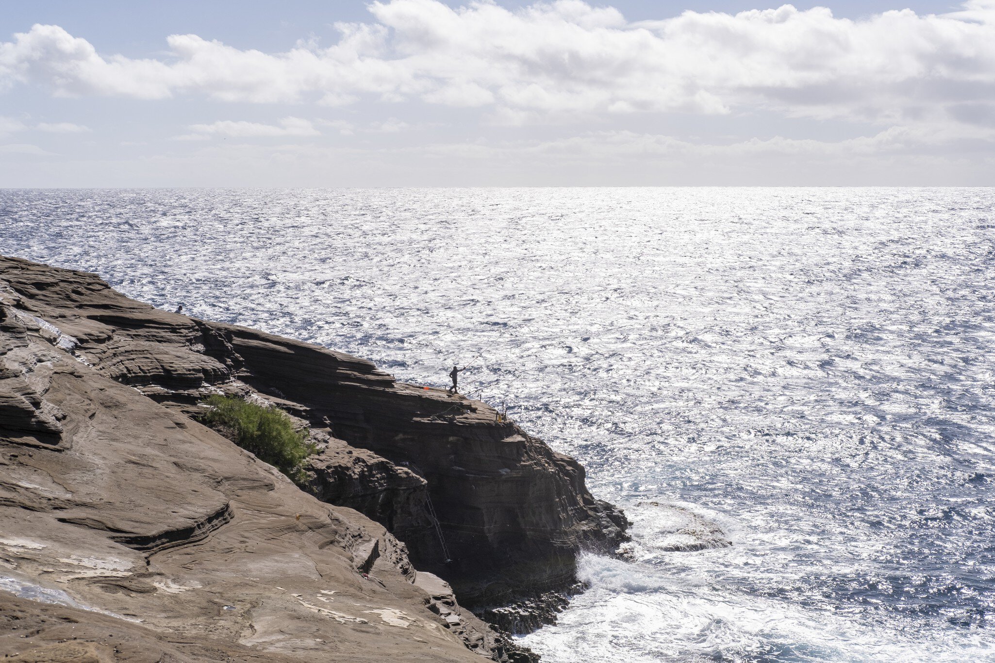 A fisherman casting a line from the cliffs at Spitting Caves, East Oahu, Hawaii