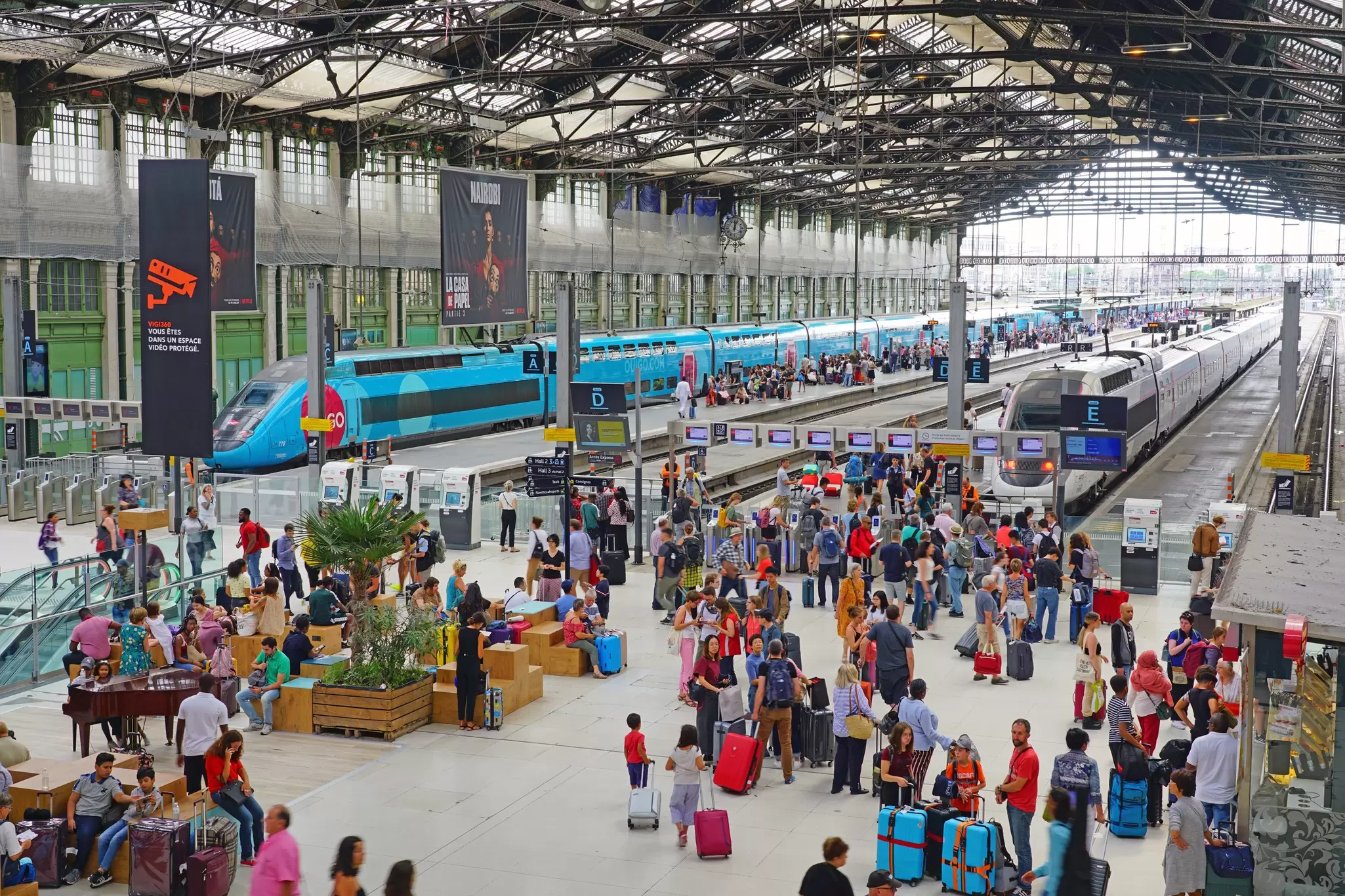 Passengers at the Gare de Lyon train station in Paris, France, with a blue train in the background. 