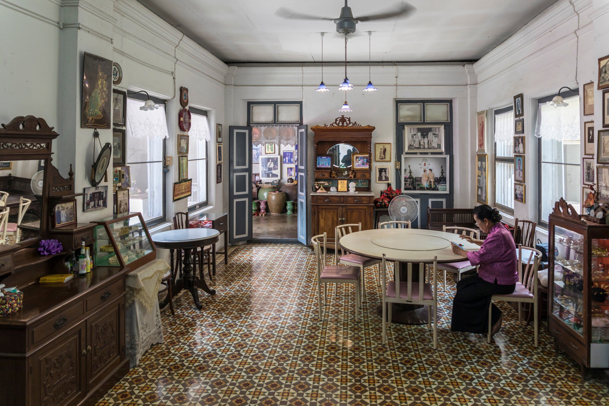 Interior view of the Chinpracha House with a sino portuguese architecture in Phuket, Thailand. Woman sitting at table on right side of frame.