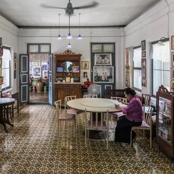 Interior view of the Chinpracha House with a sino portuguese architecture in Phuket, Thailand. Woman sitting at table on right side of frame.