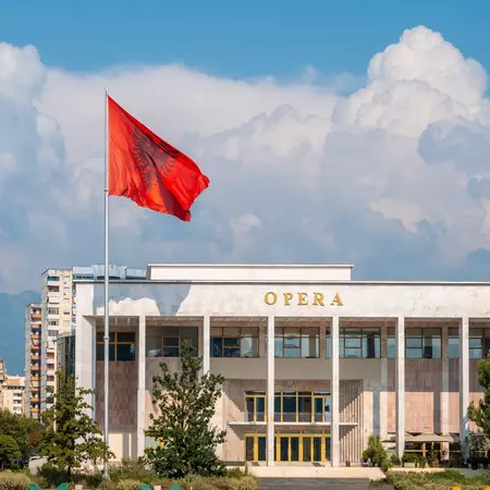 Palace of Culture or Opera on Skanderbeg Square in Tirana and the flag of Albania moving in the wind, License Type: media, Download Time: 2025-02-19T20:28:10.000Z, User: rhylton_redventures, Editorial: false, purchase_order: 56530 - Guidebooks, job: Lonely Planet WIP, client: Lonely Planet WIP, other: Rhianydd Hylton