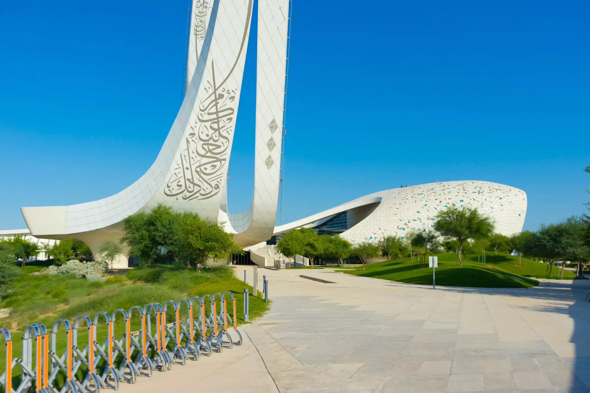 Two tall white calligraphy-carved minarets rise above the curved roof of the Education City mosque in Doha