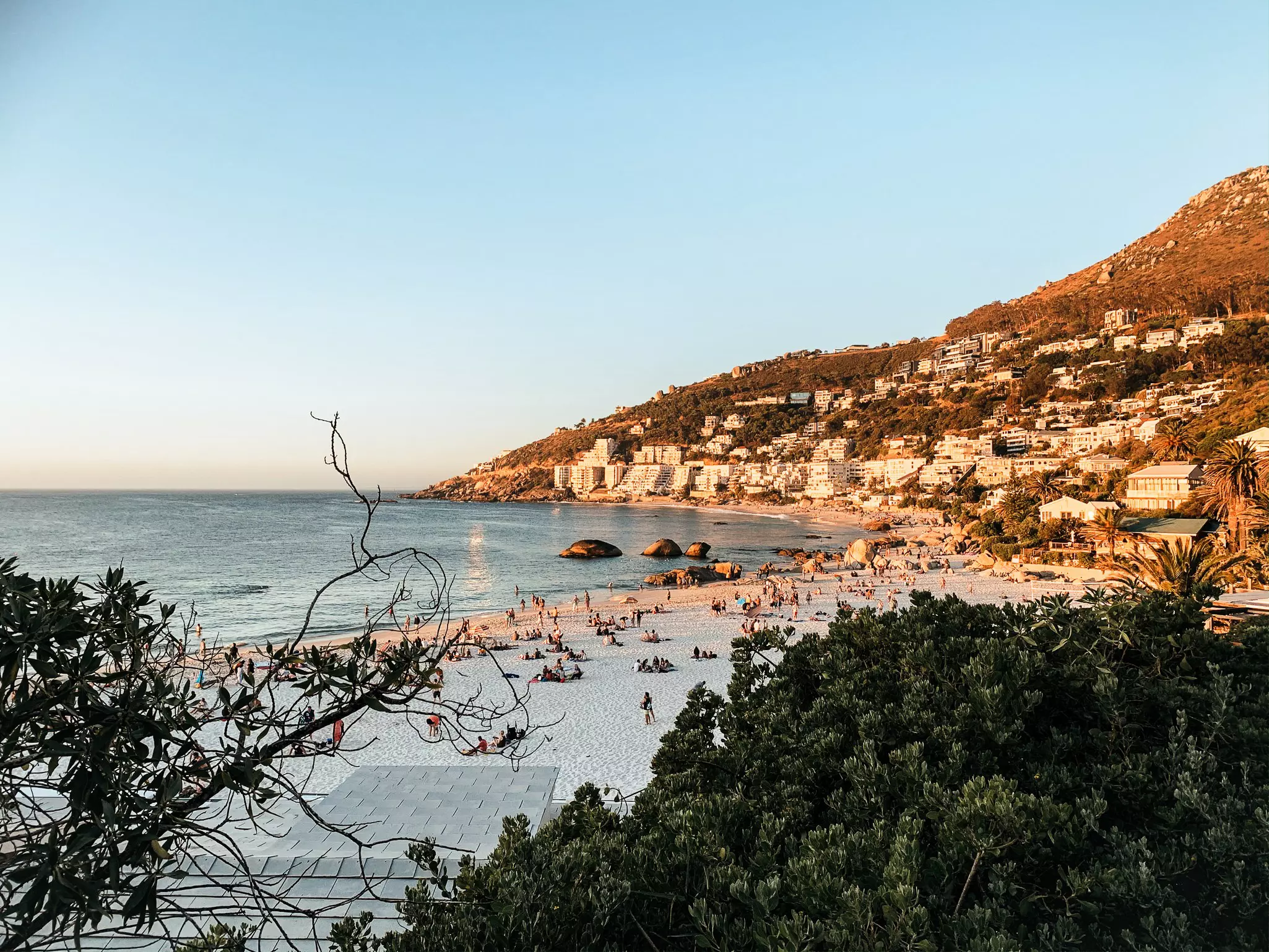 People relaxing on a white-sand beach glowing in the setting sun.