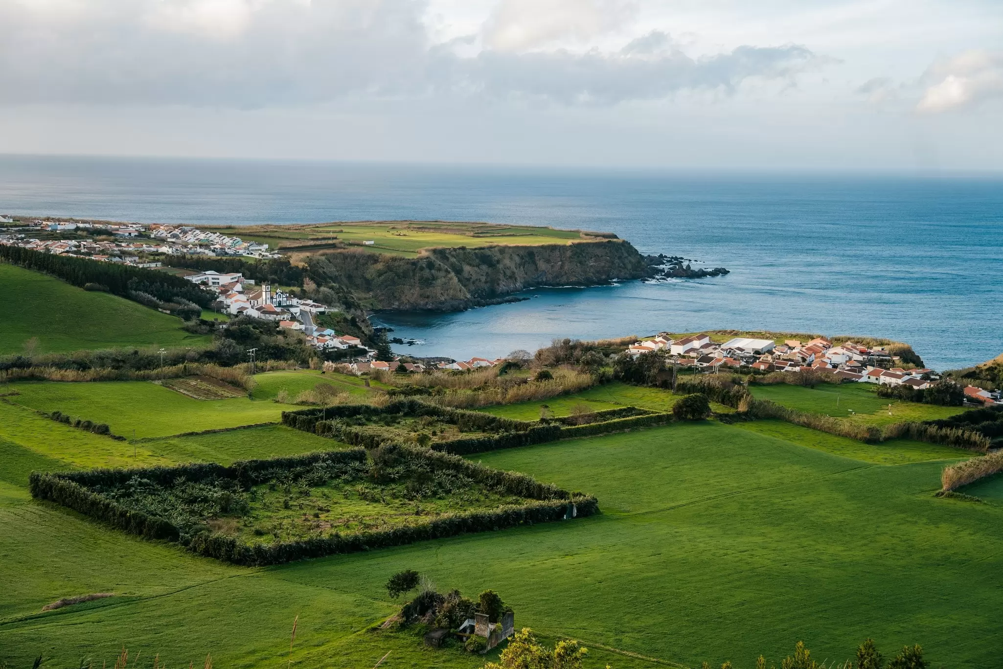 Beautiful nature view on Azores with small villages, tows, green nature fields, and blue ocean. View of typical Azores village in Sao Miguel island, Azores, Portugal.