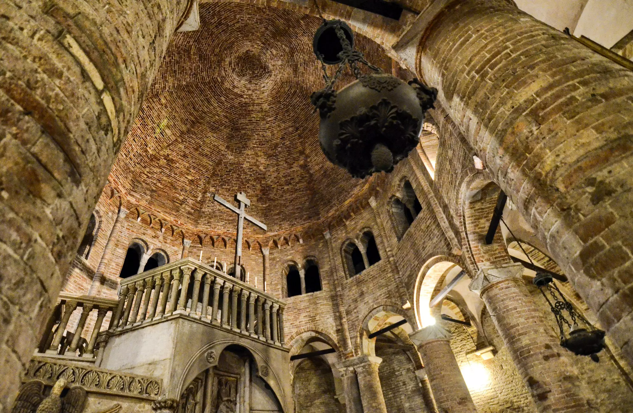 Inside a medieval cathedral with stone walls and a wooden cross overlooking an inner courtyard
