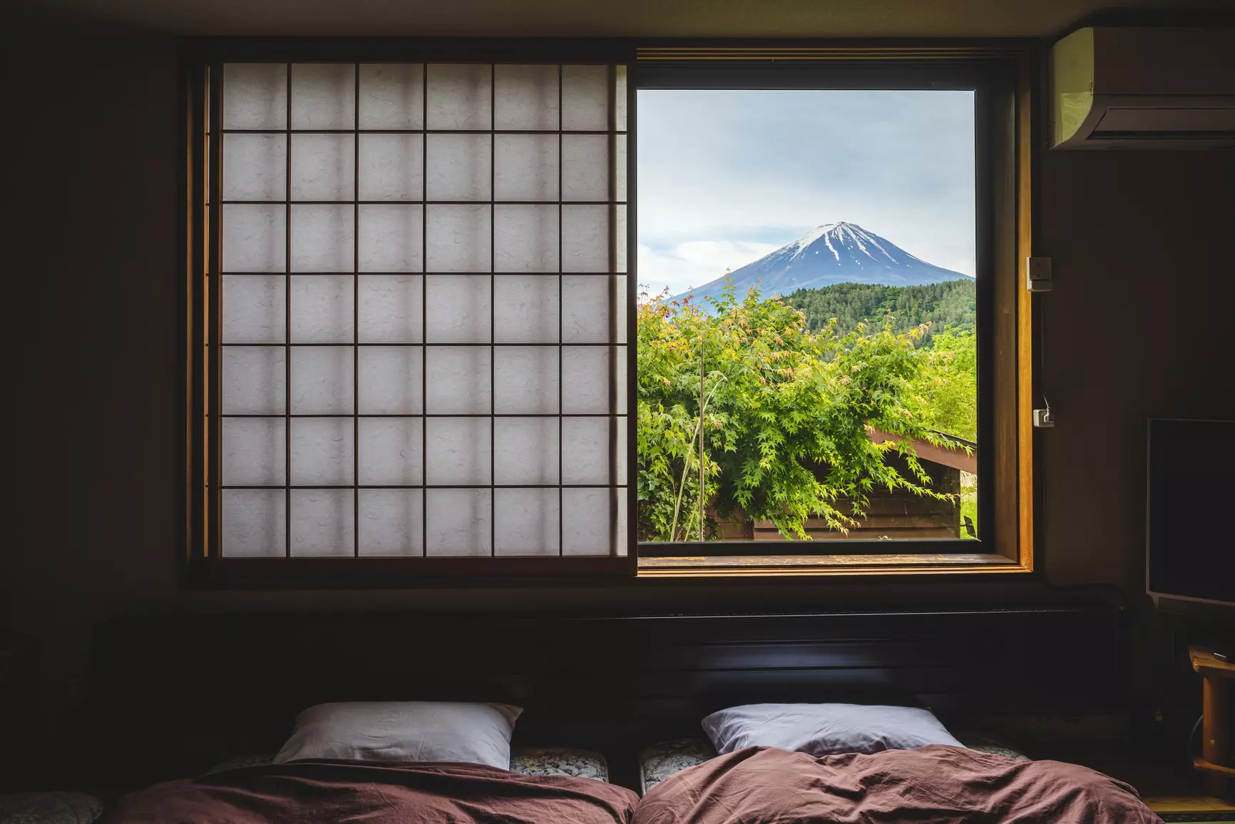 A snow-capped mountain peak framed by a window in a small Japanese inn.