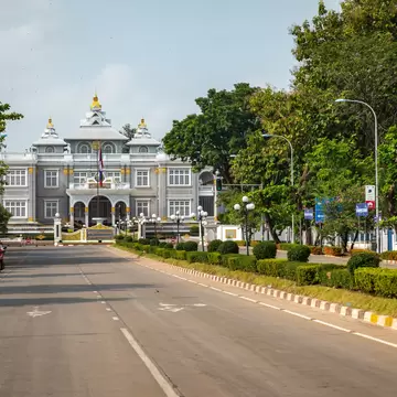 Grey-and-gold Presidential Palace behind its ornate gates at the end of a quiet tree-lined avenue in Vientiane.