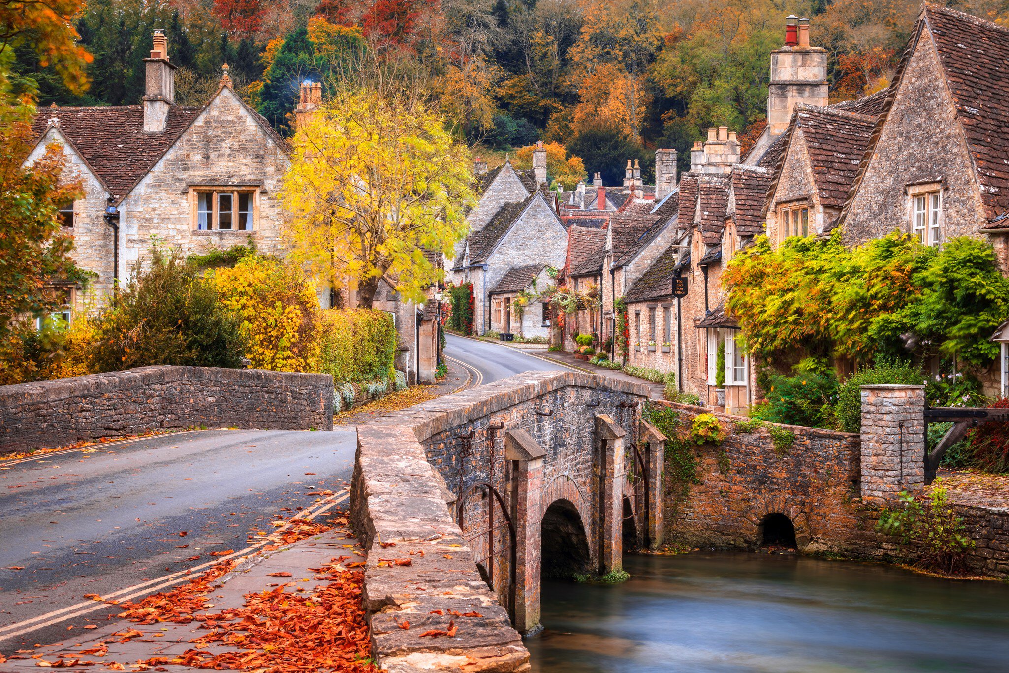 A stone bridge over Bybrook River in Castle Combe in autumn.