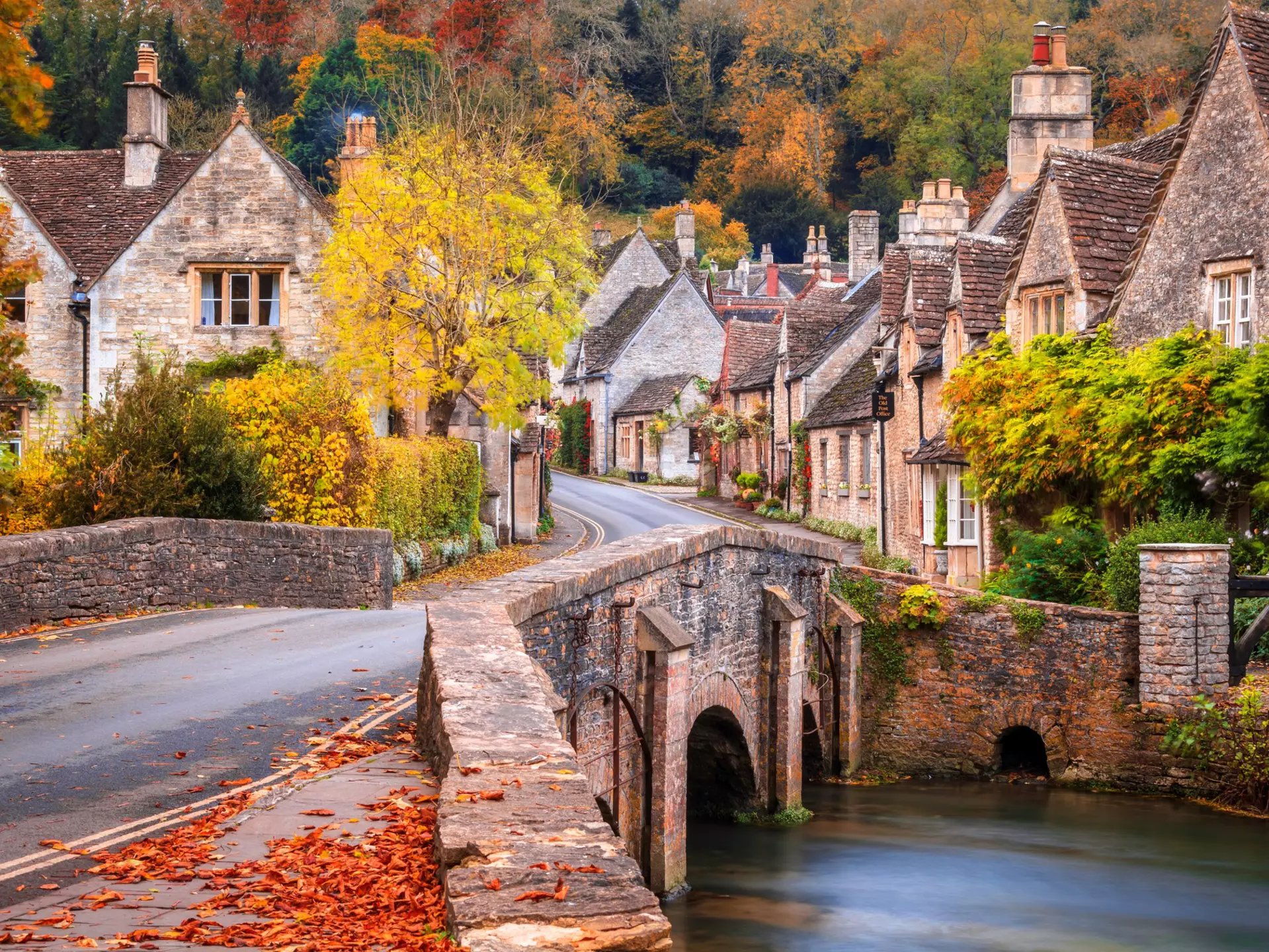 A stone bridge over Bybrook River in Castle Combe in autumn.