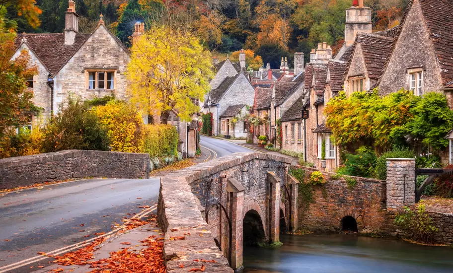 A stone bridge over Bybrook River in Castle Combe in autumn.