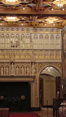 Gold tapestries, carvings and sculptures are displayed on a castle wall.