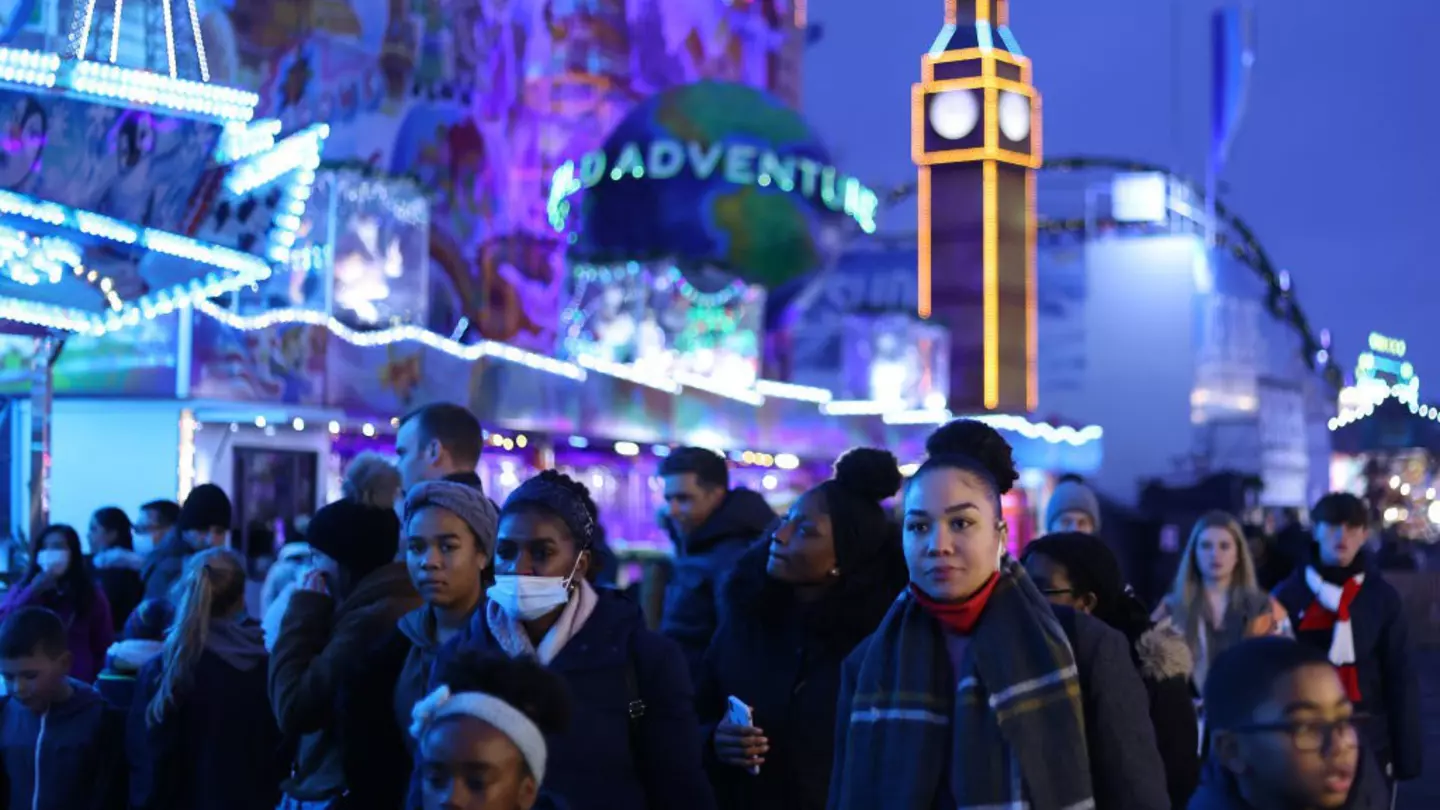 The outside of the London Review Bookshop. It's raining and a child walks past with a green umbrella. The inside of the store is lit up in a warm yellow and there are customers inside.