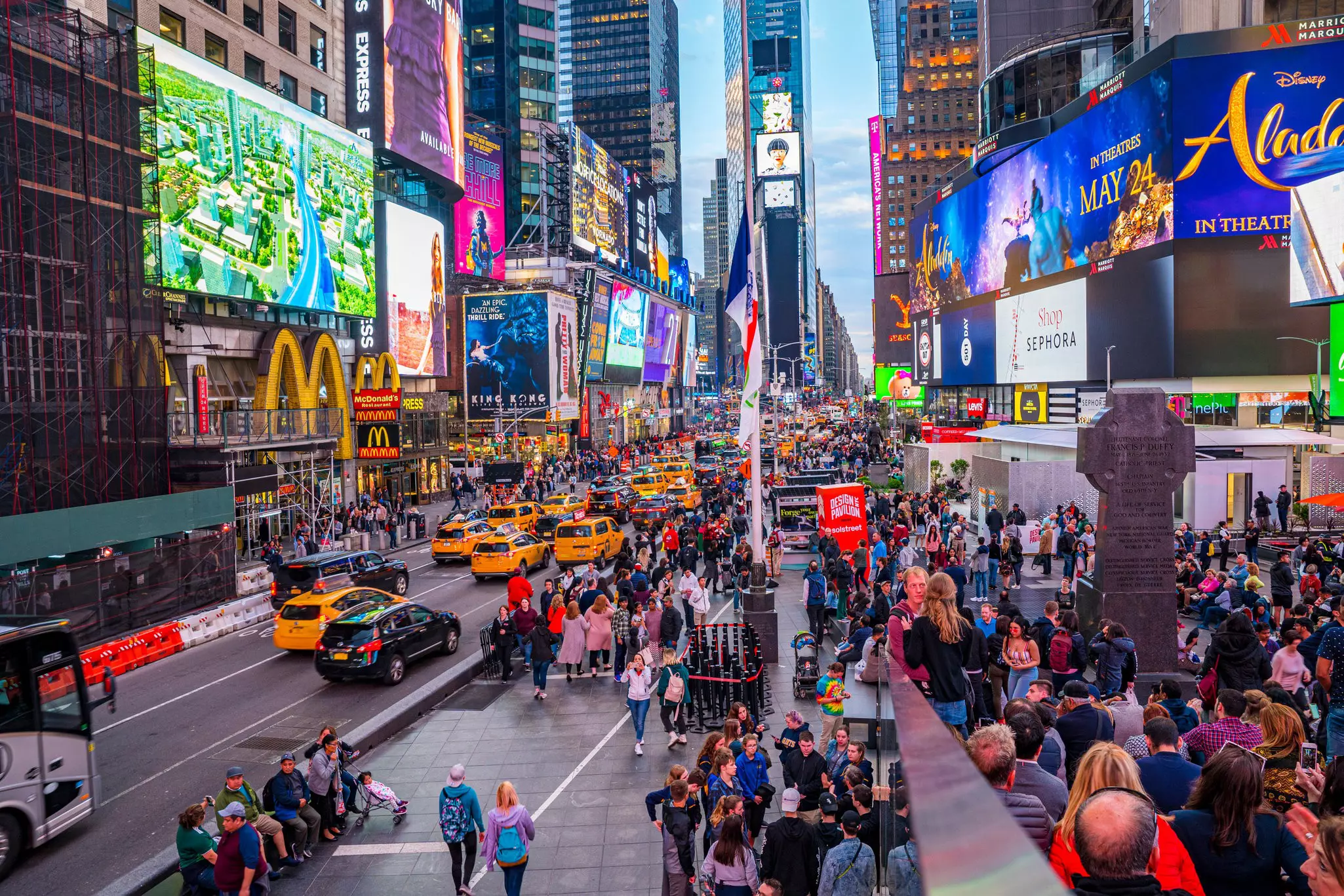 Time Square crowded in the early evening with pedestrians and traffic.