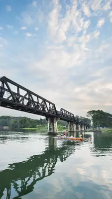 A boat travels under a steel bridge over a river 