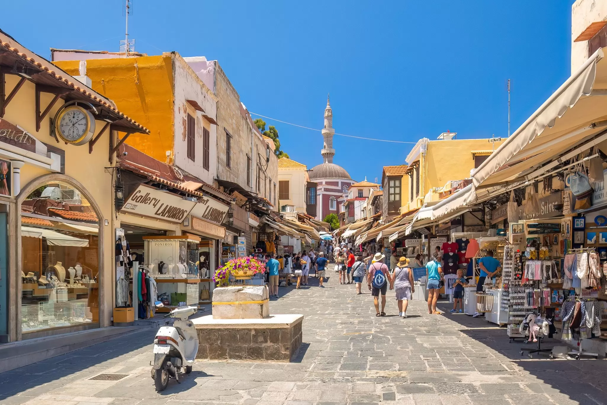 A pedestrianised street lined with shops, many of which have canopies over the entrance.