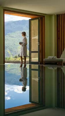 A woman in a robe in a doorway by a pool.