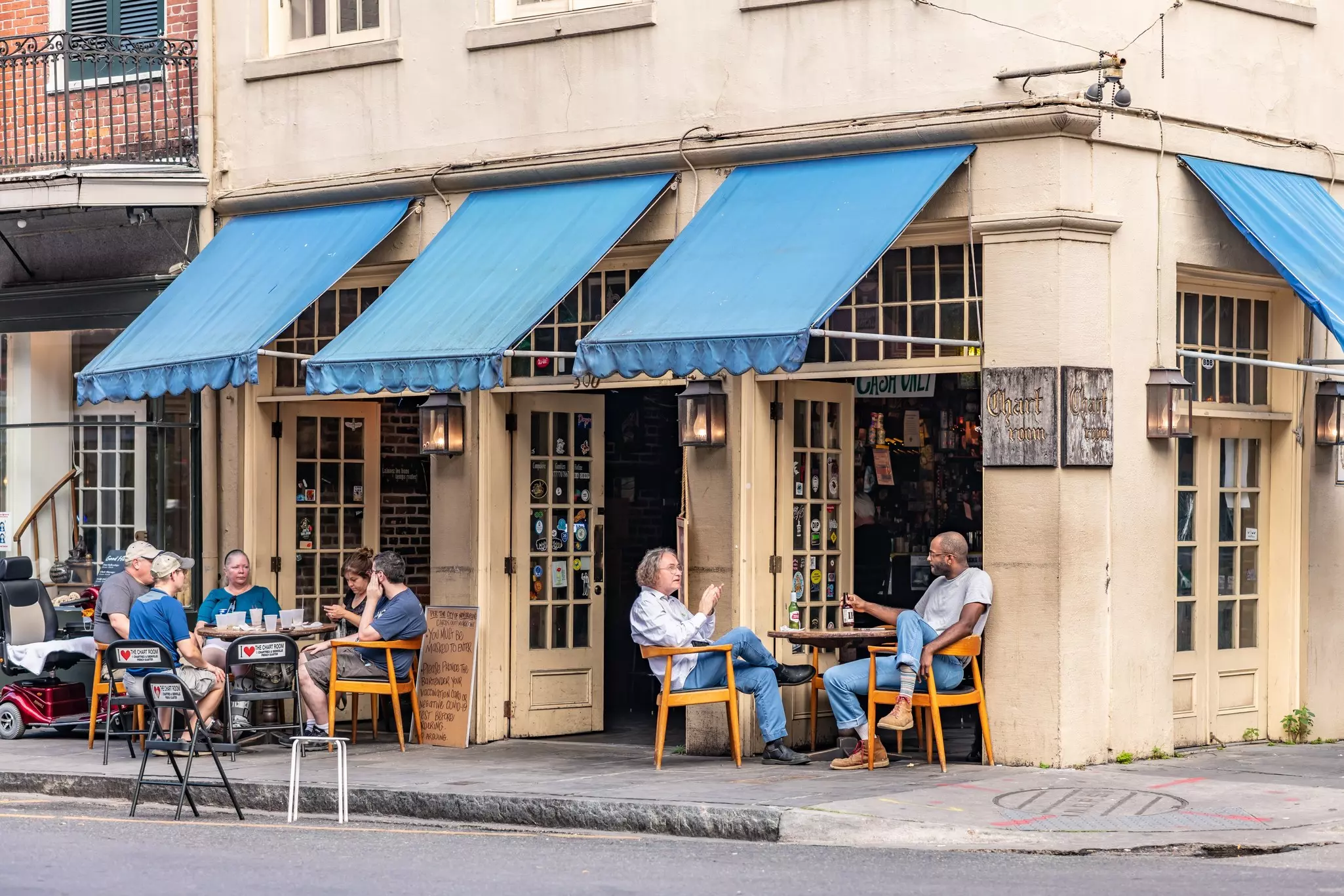 People eat outdoors at tables on a sidewalk in front of a restaurant in New Orleans, Louisiana, USA.