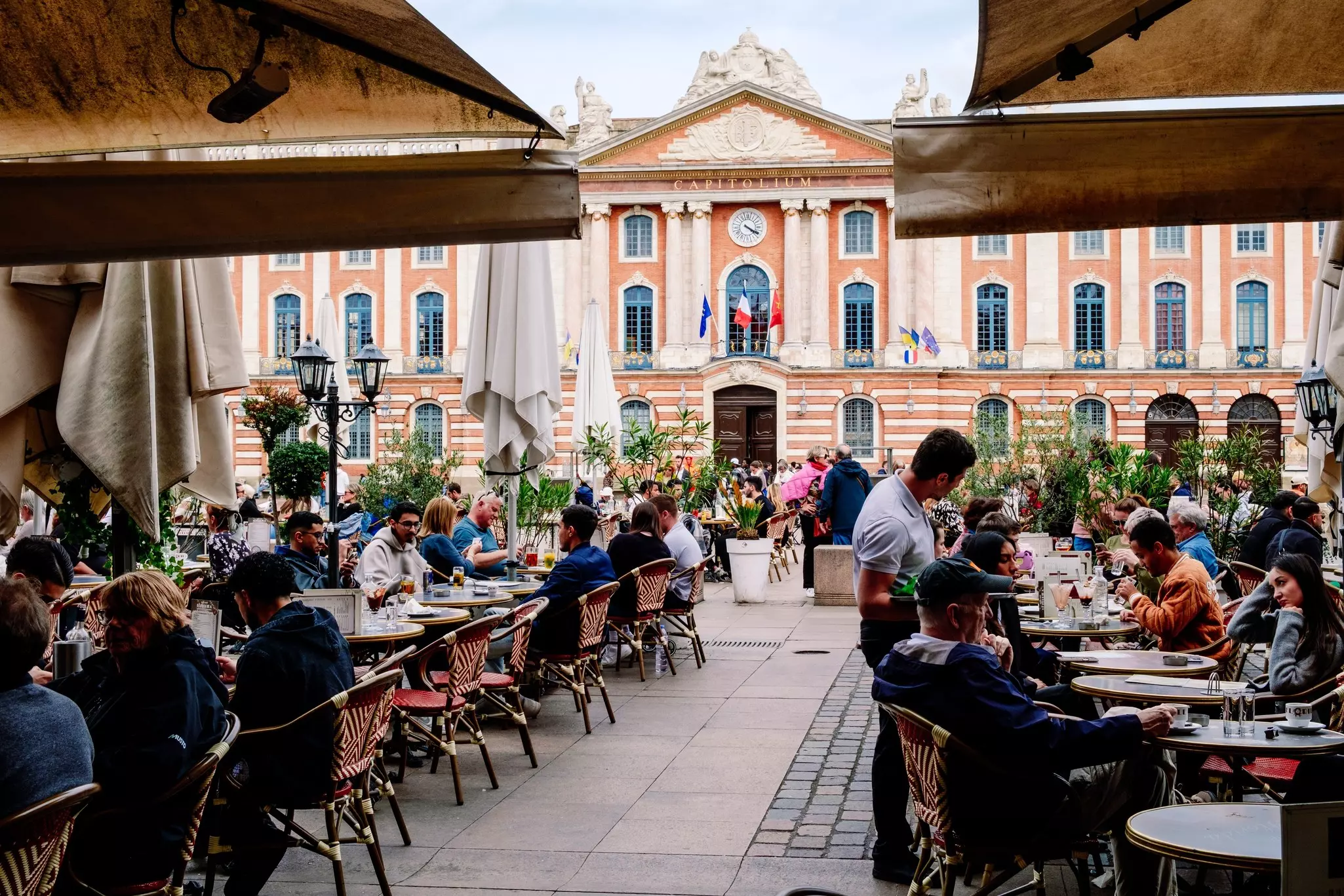 Lively plaza in Toulouse bustling with diners enjoying a leisurely meal outdoors. 