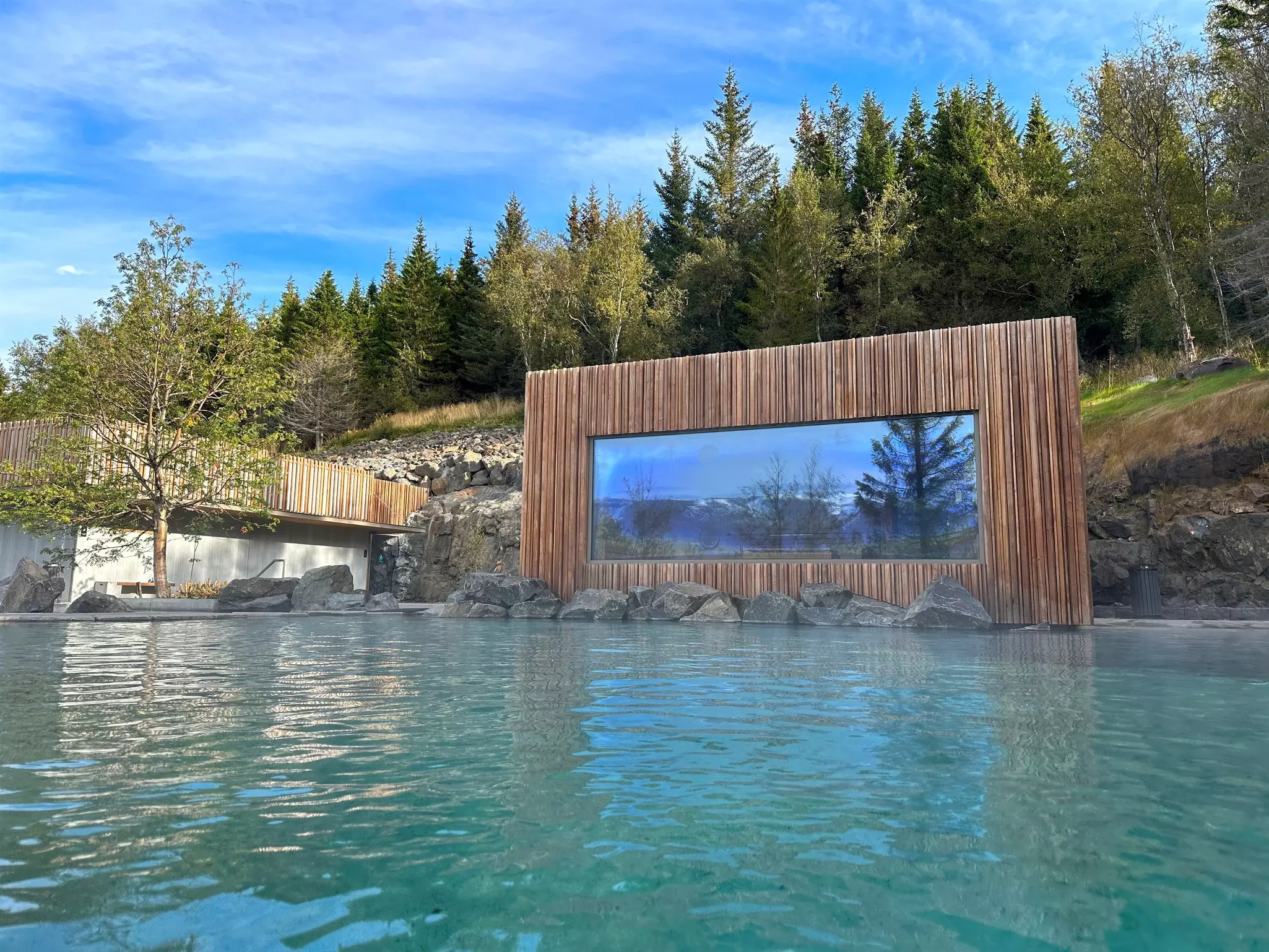 Blue and pine interiors of the Kingfisher Lodge glamping tent, including a couch, glass coffee table, double bed and bookshelves.